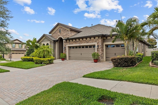 view of front of house featuring stone siding, a garage, decorative driveway, and a front yard