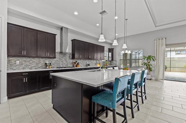kitchen featuring wall chimney exhaust hood, a sink, decorative backsplash, gas cooktop, and recessed lighting