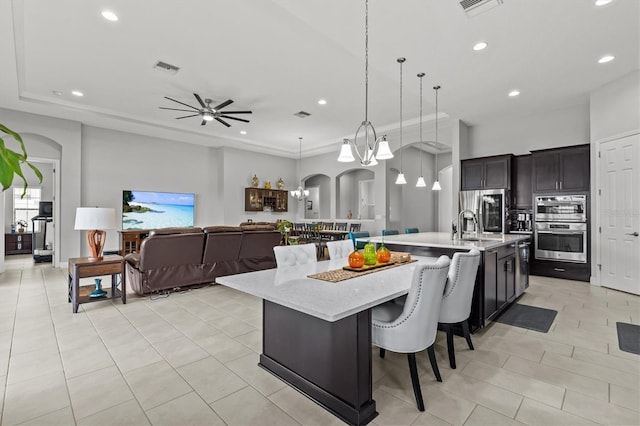 kitchen with stainless steel appliances, a large island, recessed lighting, light tile patterned floors, and arched walkways
