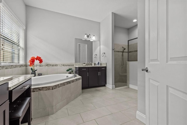bathroom with a stall shower, a bath, tile patterned flooring, vanity, and baseboards