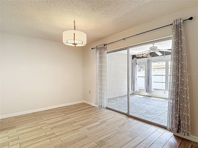 unfurnished room featuring light wood finished floors, a textured ceiling, baseboards, and ceiling fan