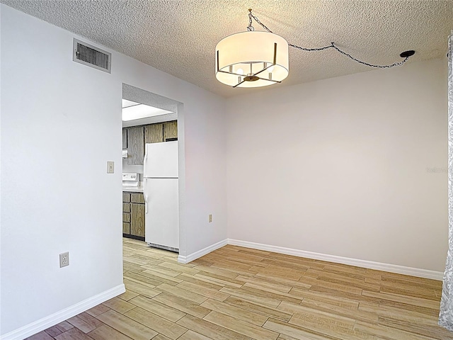 unfurnished room with light wood-style flooring, baseboards, and a textured ceiling