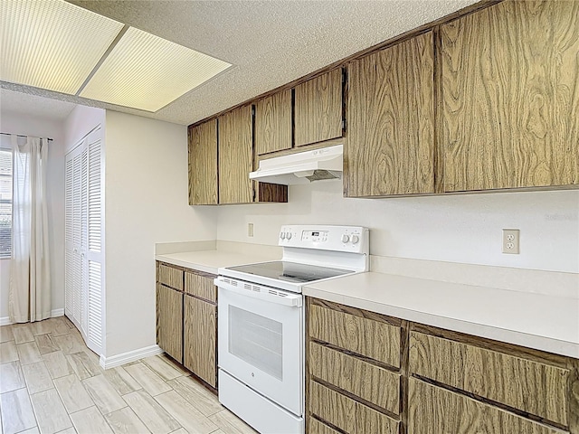 kitchen featuring white range with electric cooktop, under cabinet range hood, light countertops, and baseboards