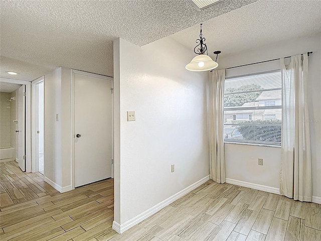 empty room featuring wood tiled floors, a textured ceiling, and baseboards