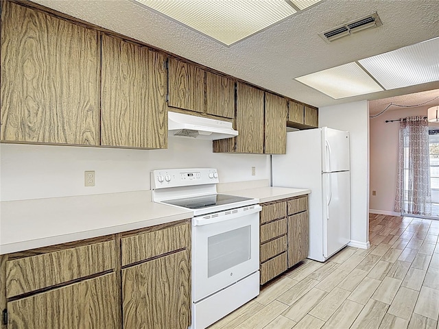 kitchen featuring white appliances, under cabinet range hood, light countertops, light wood-type flooring, and a textured ceiling