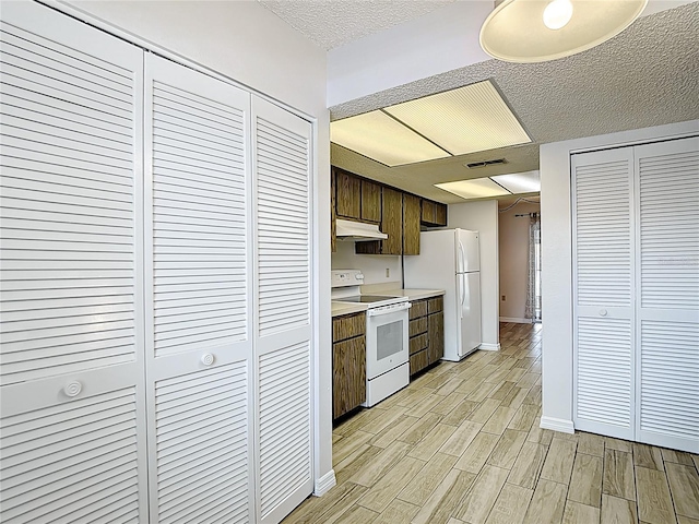 kitchen featuring white appliances, under cabinet range hood, light wood-style floors, light countertops, and baseboards
