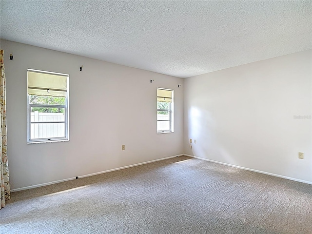 carpeted empty room featuring a textured ceiling and baseboards