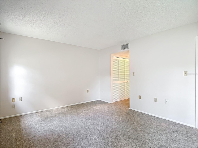 empty room featuring a textured ceiling, carpet, and baseboards