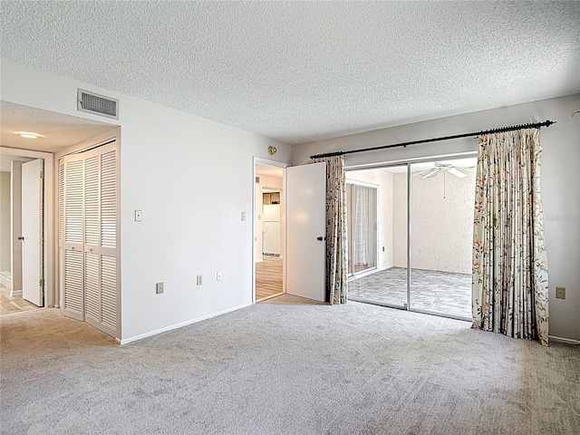 unfurnished bedroom featuring carpet, a textured ceiling, baseboards, and access to outside