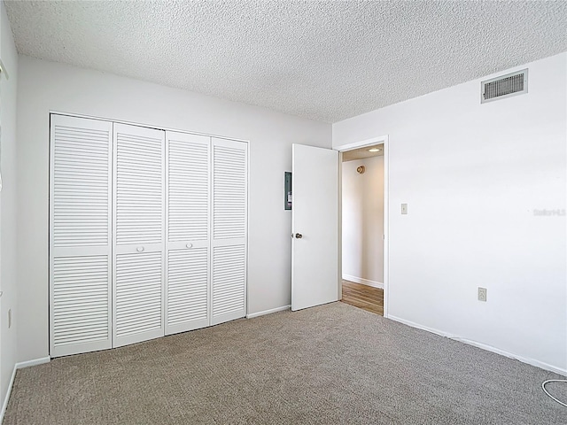 unfurnished bedroom with a closet, carpet flooring, a textured ceiling, and baseboards
