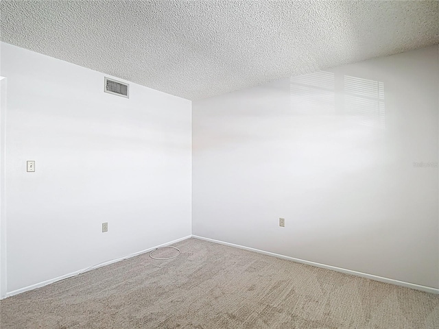 empty room with a textured ceiling, carpet, and baseboards