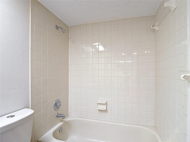 full bath featuring a textured ceiling, toilet, bathtub / shower combination, and a textured wall
