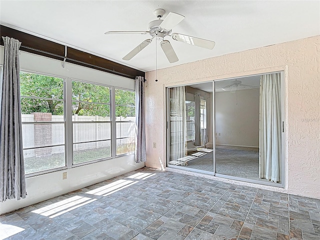 unfurnished sunroom with ceiling fan and plenty of natural light
