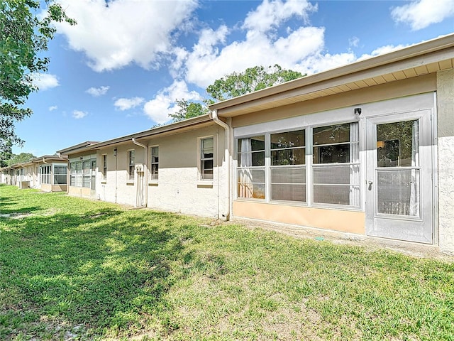 back of house featuring stucco siding and a yard