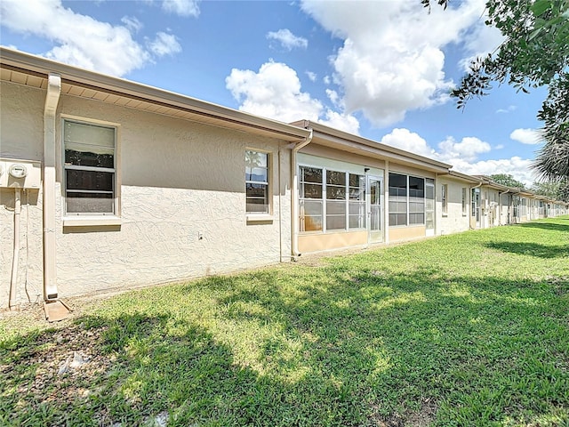 back of house featuring stucco siding and a yard