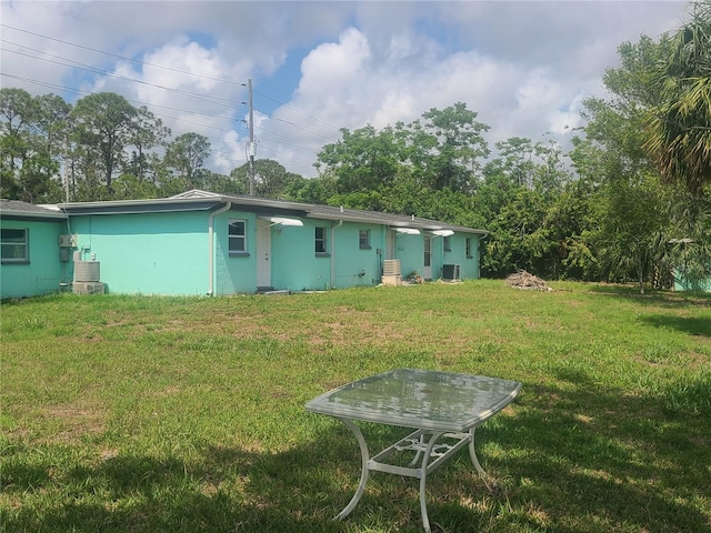 back of house featuring a lawn, stucco siding, and cooling unit