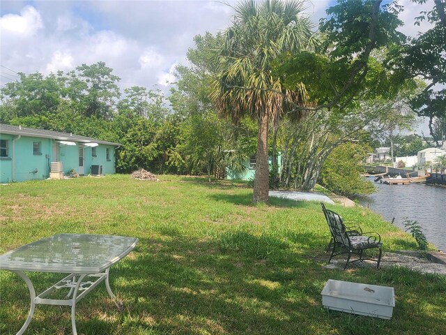 view of green lawn featuring a water view and cooling unit