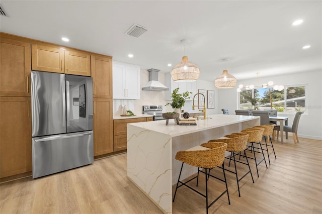 3801 Dr Martin Luther King Jr St N, Saint Petersburg, FL 33703 - kitchen featuring stainless steel appliances, wall chimney exhaust hood, light wood-type flooring, light stone counters, and recessed lighting