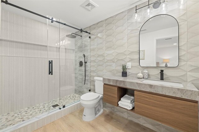 3801 Dr Martin Luther King Jr St N, Saint Petersburg, FL 33703 - bathroom featuring tile walls, a shower stall, wood finished floors, toilet, and vanity