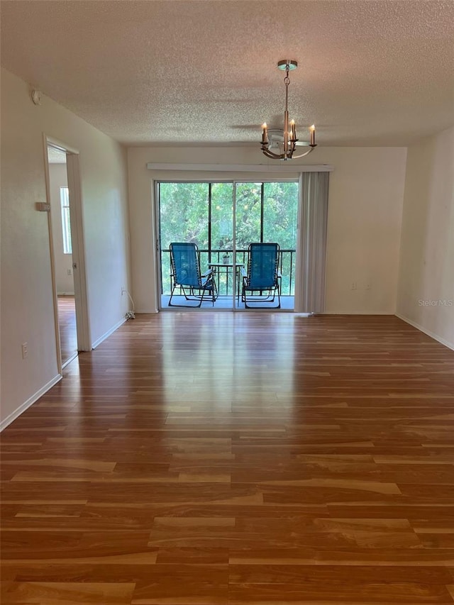 210 Cypress Ct Unit 122, Oldsmar, FL 34677 - empty room featuring wood finished floors, a chandelier, a textured ceiling, and baseboards