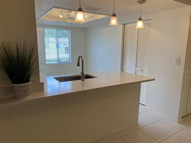 210 Cypress Ct Unit 122, Oldsmar, FL 34677 - kitchen featuring a sink, decorative light fixtures, a textured ceiling, a tray ceiling, and light tile patterned floors