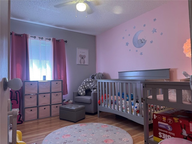 210 Cypress Ct Unit 122, Oldsmar, FL 34677 - bedroom featuring wood finished floors, a textured ceiling, ceiling fan, and a nursery area