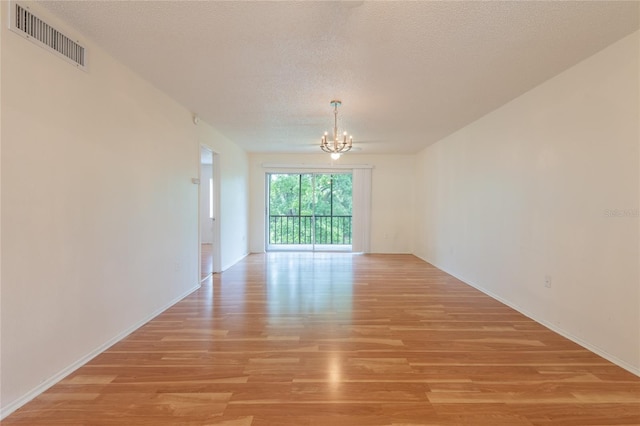 210 Cypress Ct Unit 122, Oldsmar, FL 34677 - empty room with a chandelier, light wood finished floors, and a textured ceiling