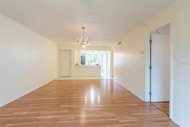 210 Cypress Ct Unit 122, Oldsmar, FL 34677 - unfurnished dining area featuring a chandelier, light wood-style floors, and a textured ceiling