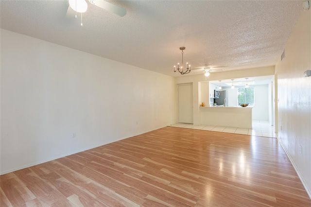 210 Cypress Ct Unit 122, Oldsmar, FL 34677 - unfurnished living room with light wood finished floors, a ceiling fan, a chandelier, and a textured ceiling