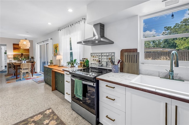 11376 119th Ter, Largo, FL 33778 - kitchen with stainless steel range with electric cooktop, wall chimney range hood, a sink, dark speckled floor, and white cabinets