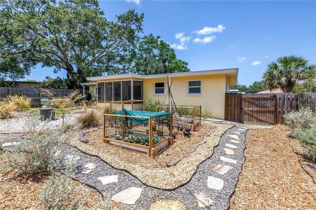 11376 119th Ter, Largo, FL 33778 - back of property featuring stucco siding, a sunroom, a gate, a vegetable garden, and fence