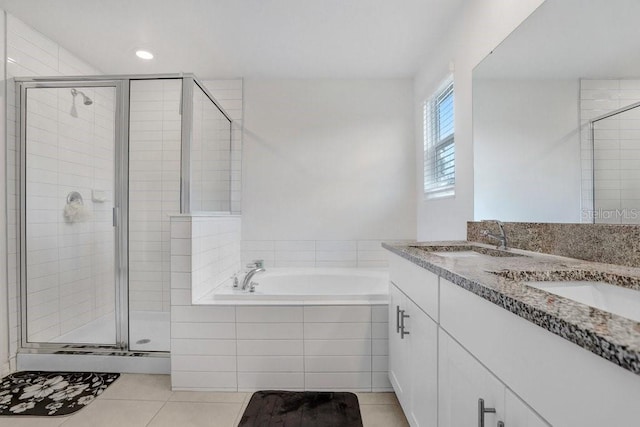 bathroom featuring a stall shower, tile patterned flooring, a bath, and double vanity