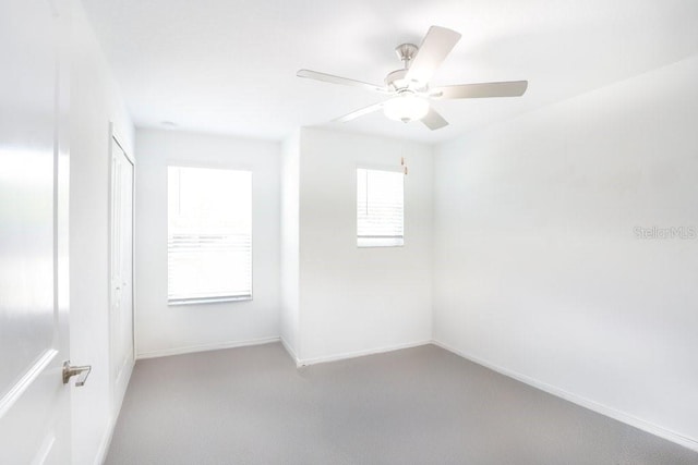carpeted empty room with baseboards and a ceiling fan