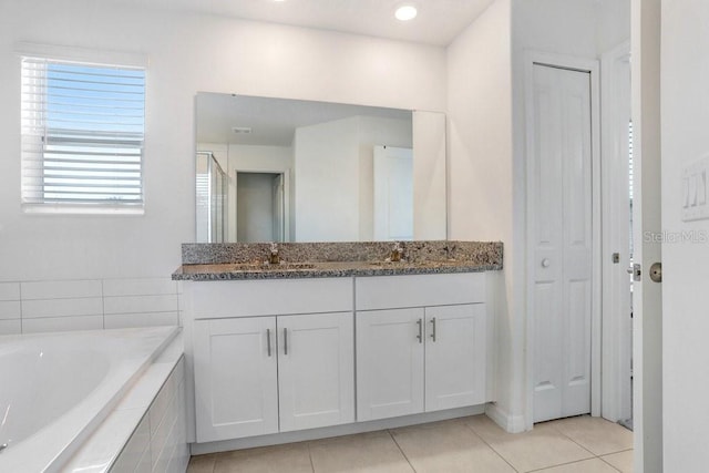 full bath with tile patterned floors, a garden tub, double vanity, and a closet