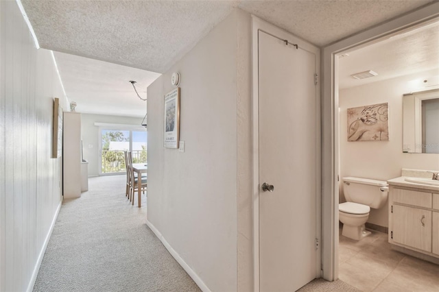 200 1st Ave Unit 406, St Pete Beach, FL 33706 - corridor with a textured ceiling, baseboards, light colored carpet, and a sink