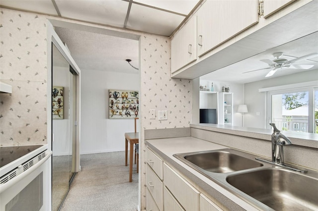 200 1st Ave Unit 406, St Pete Beach, FL 33706 - kitchen featuring a sink, wallpapered walls, light countertops, light colored carpet, and ceiling fan