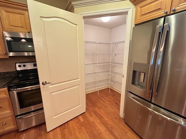 622 Seascape Way, Tampa, FL 33602 - kitchen with appliances with stainless steel finishes, light wood-style floors, a textured ceiling, and dark stone countertops