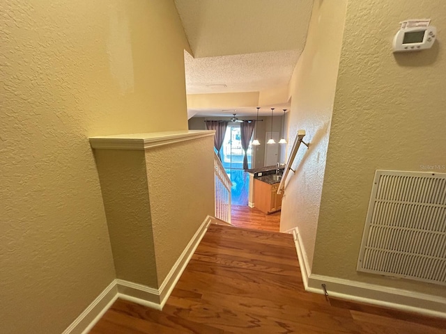 622 Seascape Way, Tampa, FL 33602 - corridor featuring wood finished floors, a textured wall, baseboards, a textured ceiling, and an upstairs landing