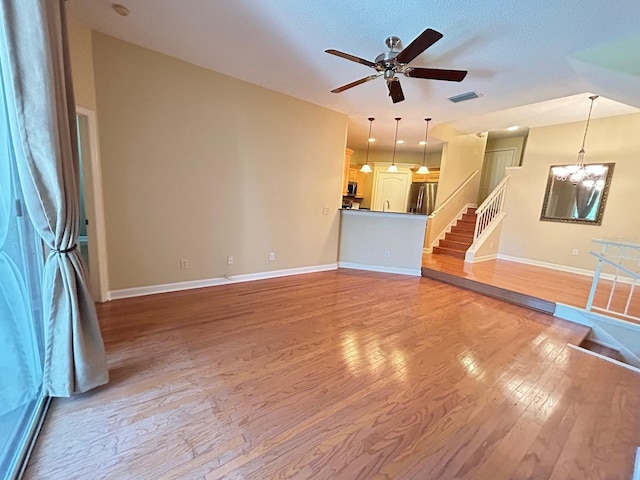 622 Seascape Way, Tampa, FL 33602 - unfurnished living room with light wood-style flooring, stairs, baseboards, ceiling fan, and a chandelier