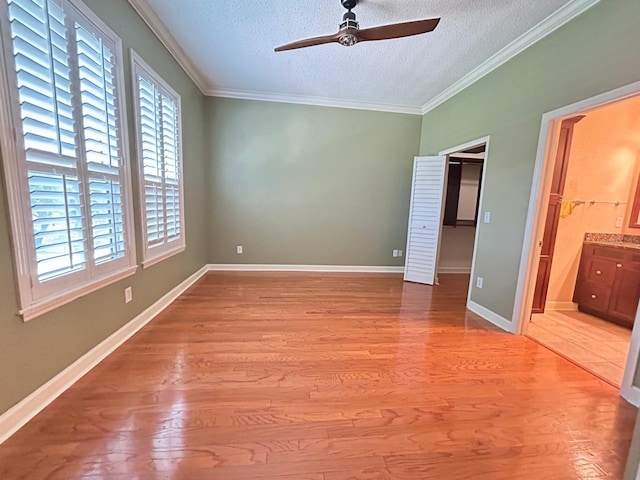 622 Seascape Way, Tampa, FL 33602 - unfurnished bedroom with a textured ceiling, light wood-type flooring, a spacious closet, crown molding, and ensuite bath