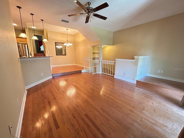 622 Seascape Way, Tampa, FL 33602 - unfurnished living room featuring wood finished floors, a ceiling fan, baseboards, lofted ceiling, and a chandelier