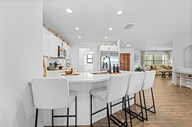 3041 Waterfall Dr, Spring Hill, FL 34608 - kitchen with stainless steel appliances, a peninsula, a breakfast bar area, white cabinets, and recessed lighting
