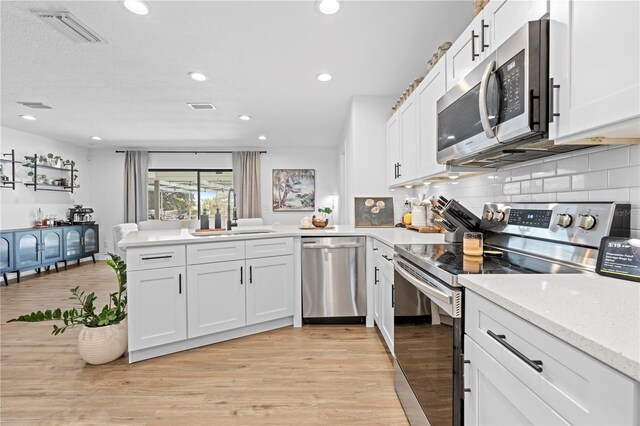 3041 Waterfall Dr, Spring Hill, FL 34608 - kitchen featuring appliances with stainless steel finishes, a sink, a peninsula, white cabinetry, and recessed lighting