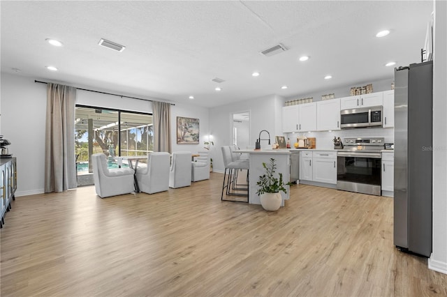 3041 Waterfall Dr, Spring Hill, FL 34608 - kitchen with stainless steel appliances, light wood-style floors, a kitchen breakfast bar, open floor plan, and recessed lighting