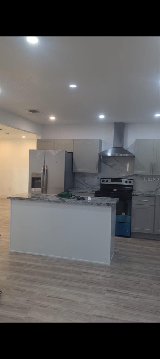 4824 Huntington St NE, Saint Petersburg, FL 33703 - kitchen featuring wall chimney exhaust hood, range with electric stovetop, stainless steel fridge with ice dispenser, decorative backsplash, and light stone counters