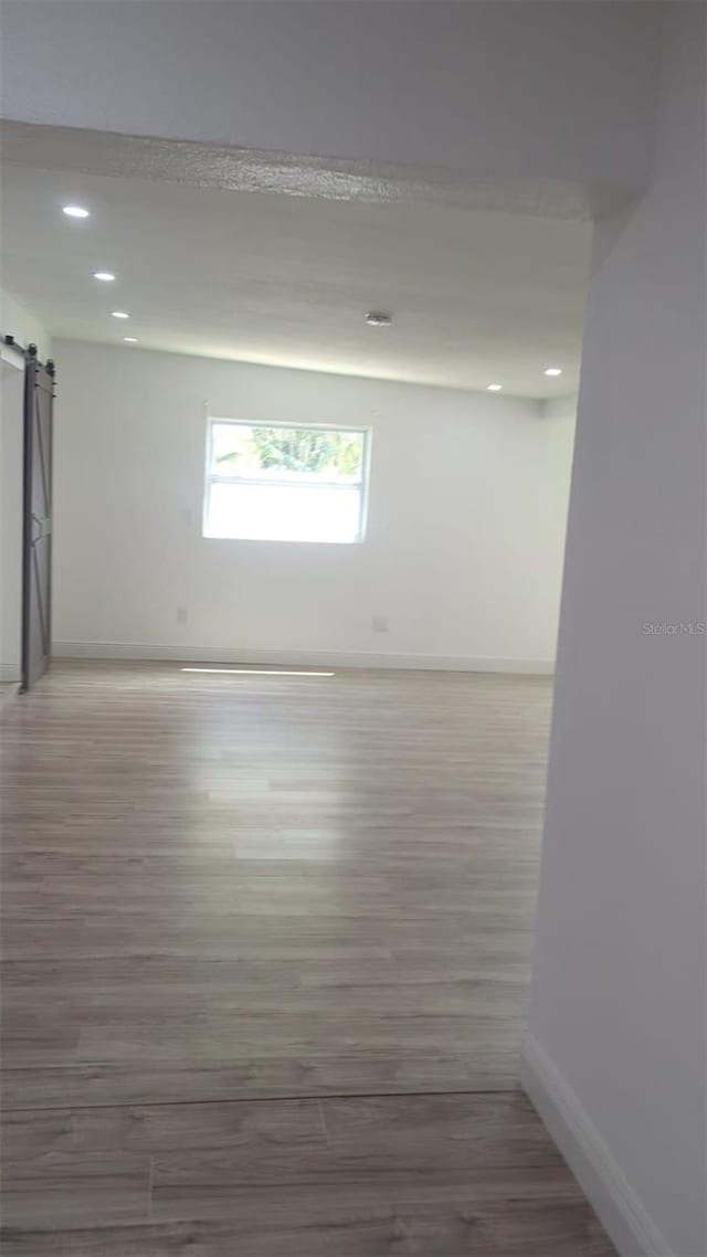 4824 Huntington St NE, Saint Petersburg, FL 33703 - spare room featuring a barn door, baseboards, wood finished floors, and recessed lighting