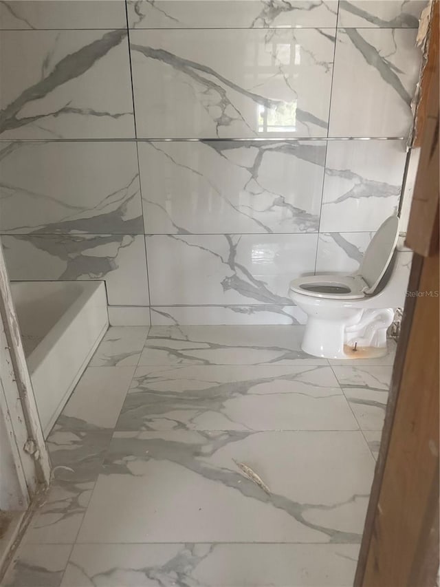 4824 Huntington St NE, Saint Petersburg, FL 33703 - full bath with marble look tiles, toilet, and a tub to relax in