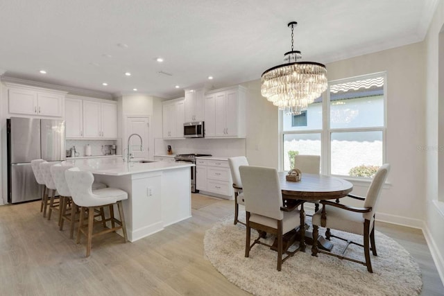 5410 Morey Farms Loop, Palmetto, FL 34221 - kitchen with stainless steel appliances, light wood-style floors, an island with sink, a chandelier, and a breakfast bar area