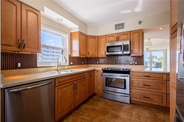 2530 Gary Cir Unit 301, Dunedin, FL 34698 - kitchen with appliances with stainless steel finishes, a sink, backsplash, light stone counters, and brown cabinets