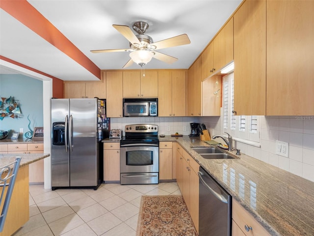 4700 Cove Cir Unit 301, Saint Petersburg, FL 33708 - kitchen featuring appliances with stainless steel finishes, a sink, light brown cabinetry, decorative backsplash, and light stone counters